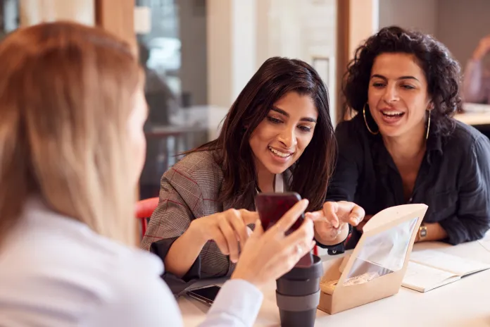 Three women gathering around a smartphone